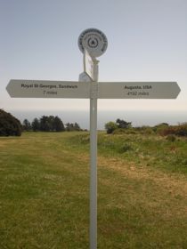 A white signpost to Royal St George's at Sandwich and Augusta, USA on the golf course at Walmer and Kingsdown Golf Club.
