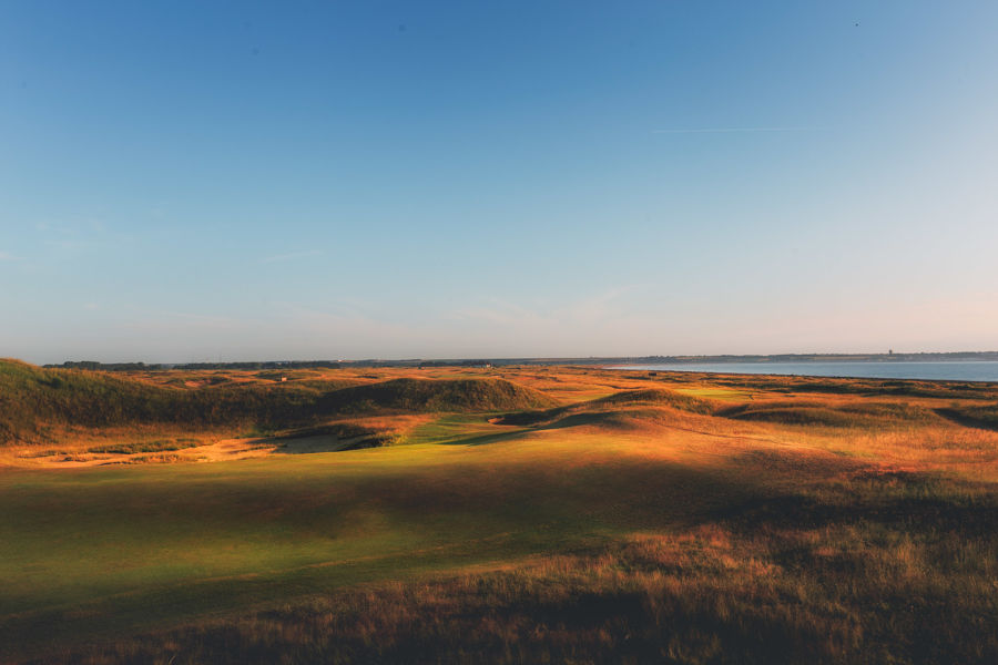 Rolling dunes, fairways and greens with Sandwich Bay in the distance.