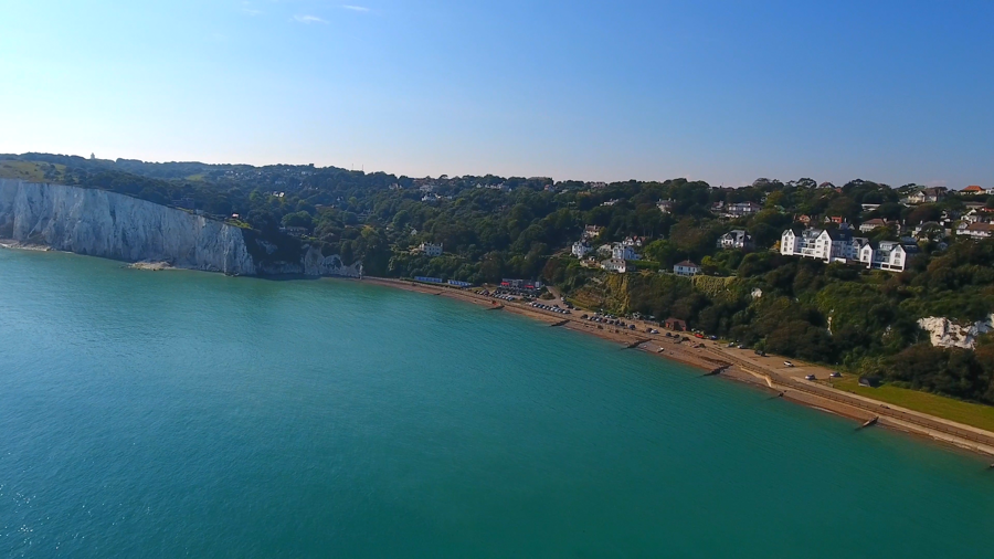 The sweeping St Margaret's Bay beach with white cliffs to the left and houses on the slope down to the beach.