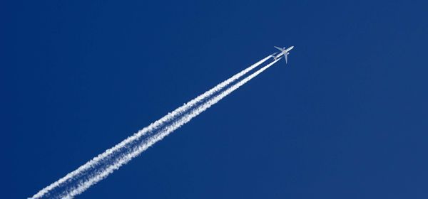 Passenger jet in a deep blue sky with contrail.