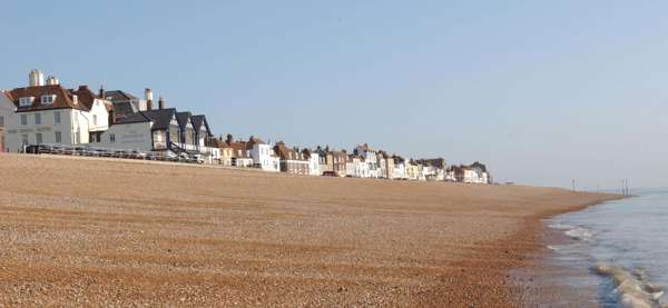 Deal seafront showing pebble beach and cottagers on the sky line.