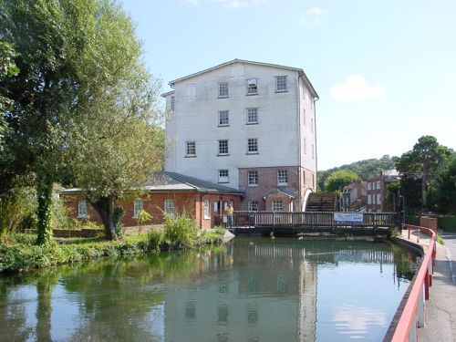A mill with water wheel and a river in the foreground