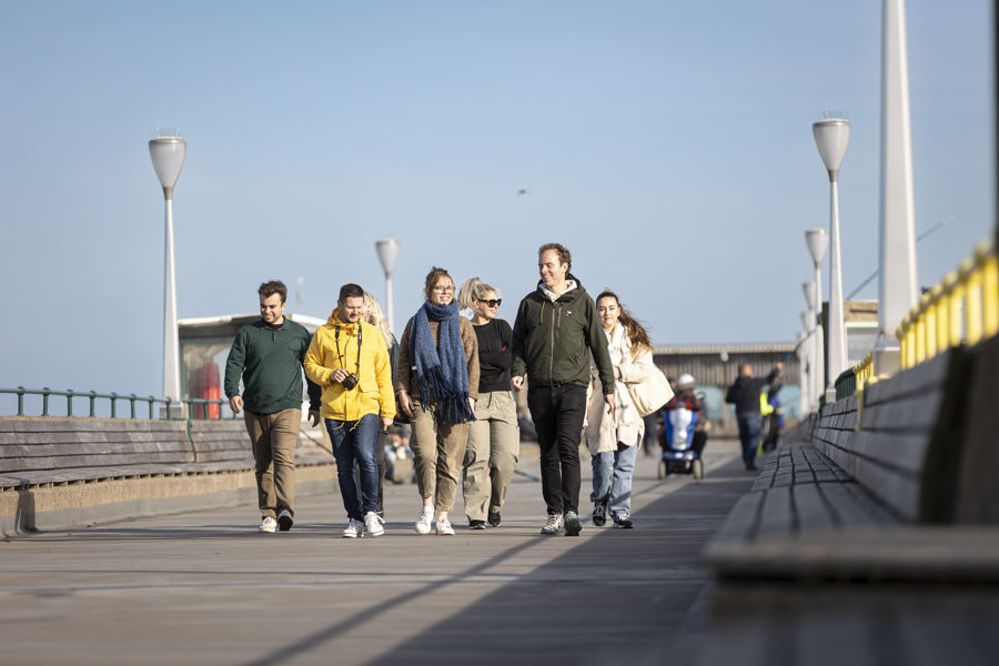 A group of people in winter coats walking on Deal Pier.