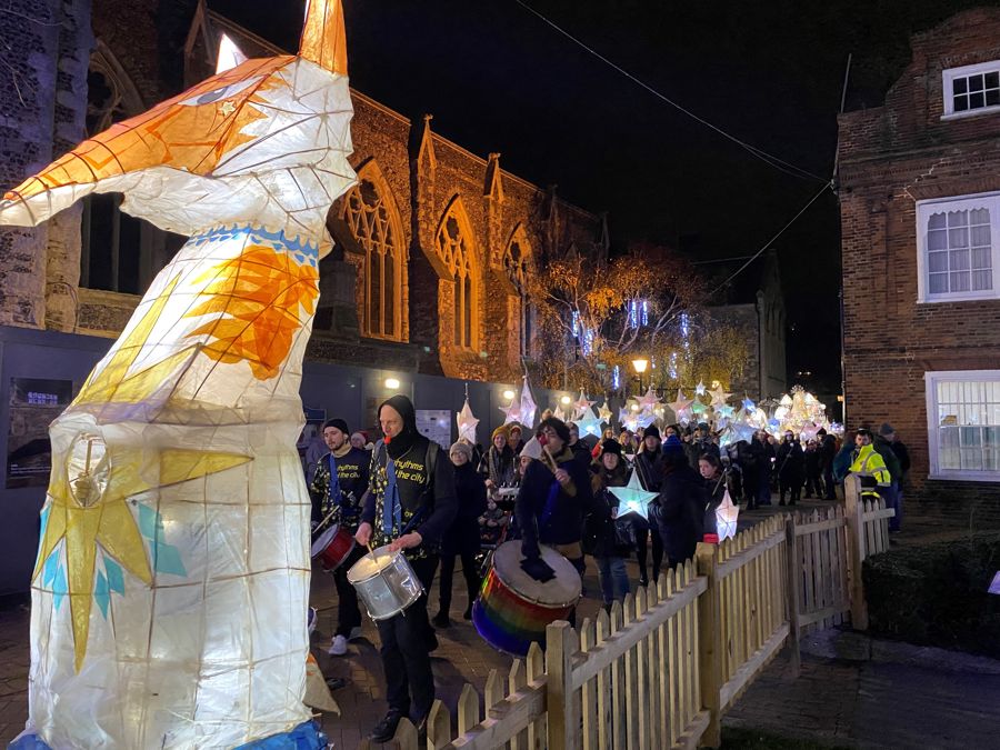 A lantern parade of star-shaped lanterns headed by a large fox lantern and drummers.