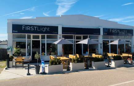 Exterior image of Firstlight Cafe Terrace with tables, chairs and umbrellas