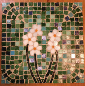 A mosaic tile made of green, white and blue pieces of ceramic forming the image of flowers.