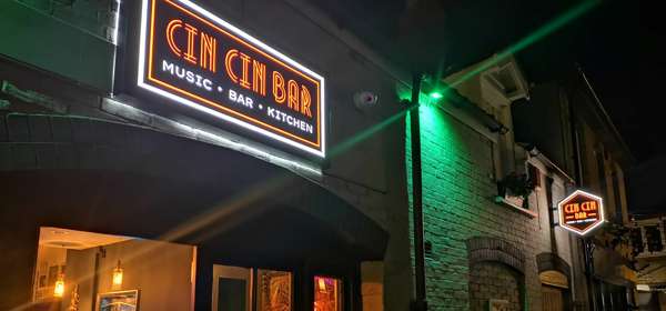 Entrance of Cin Cin bar at night with neon sign.