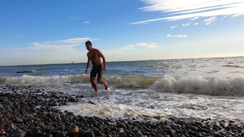 A man emerging from the sea after a swim