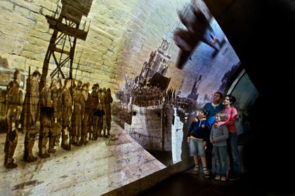 A family group looking at a projection of a World War scene onto a wartime tunnel.