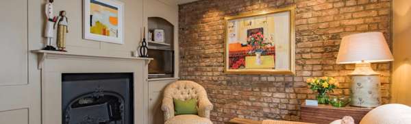 Sitting room with fire place, exposed brick wall with hung painting