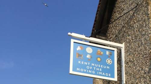 A shingle sign for the museum on a pebbles-dashed gable wall