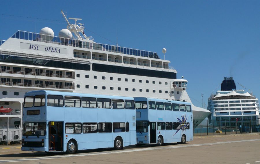 Two double-decker buses parked in front of a cruise ship docked in the Port of Dover.