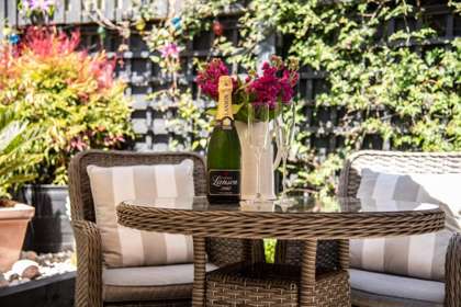 Garden table with two chairs, champagne and two glasses.
