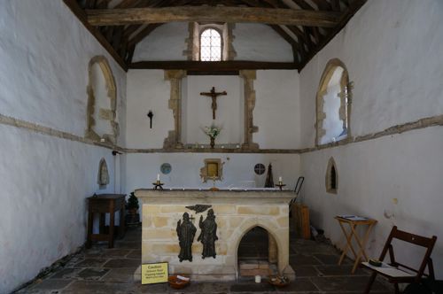 The interior of St Edmunds Chapel with a rough stone floor, whitewashed walls and a central stone alter.