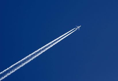 Passenger jet in a deep blue sky with contrail.