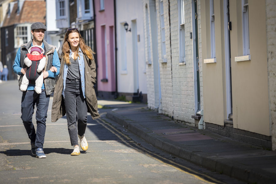 A couple with a baby walking arm in arm through the colourful streets of Deal's conservation area.