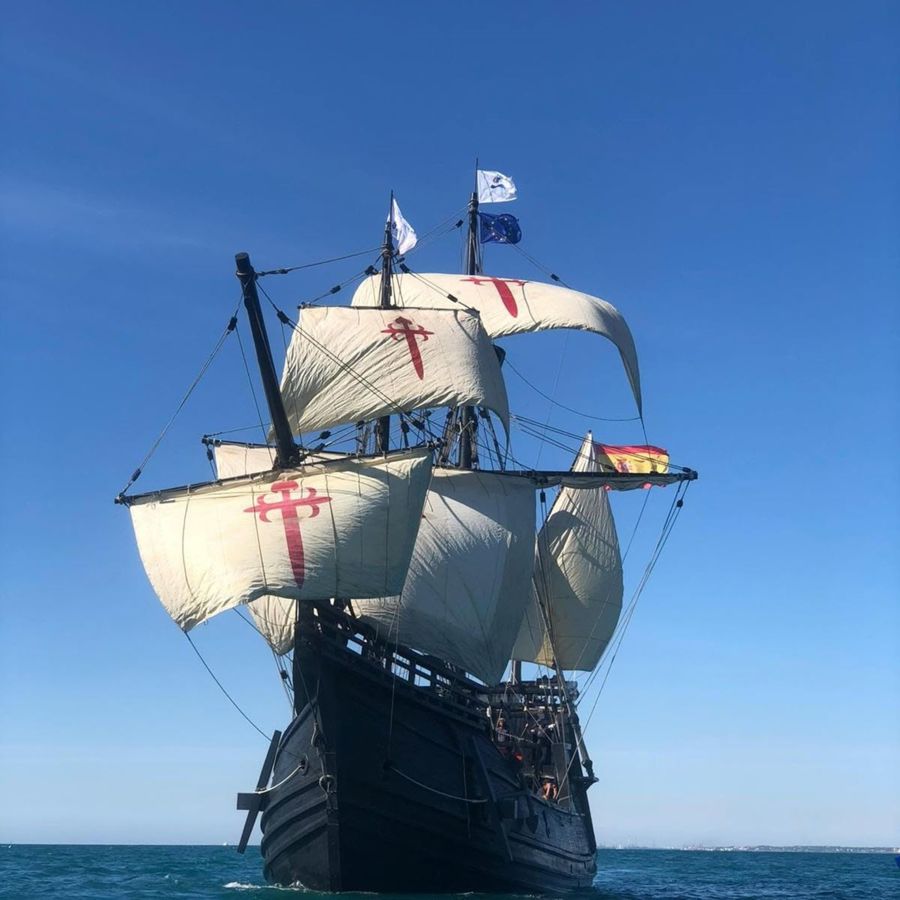 A replica wooden ship in full sail on the sea.
