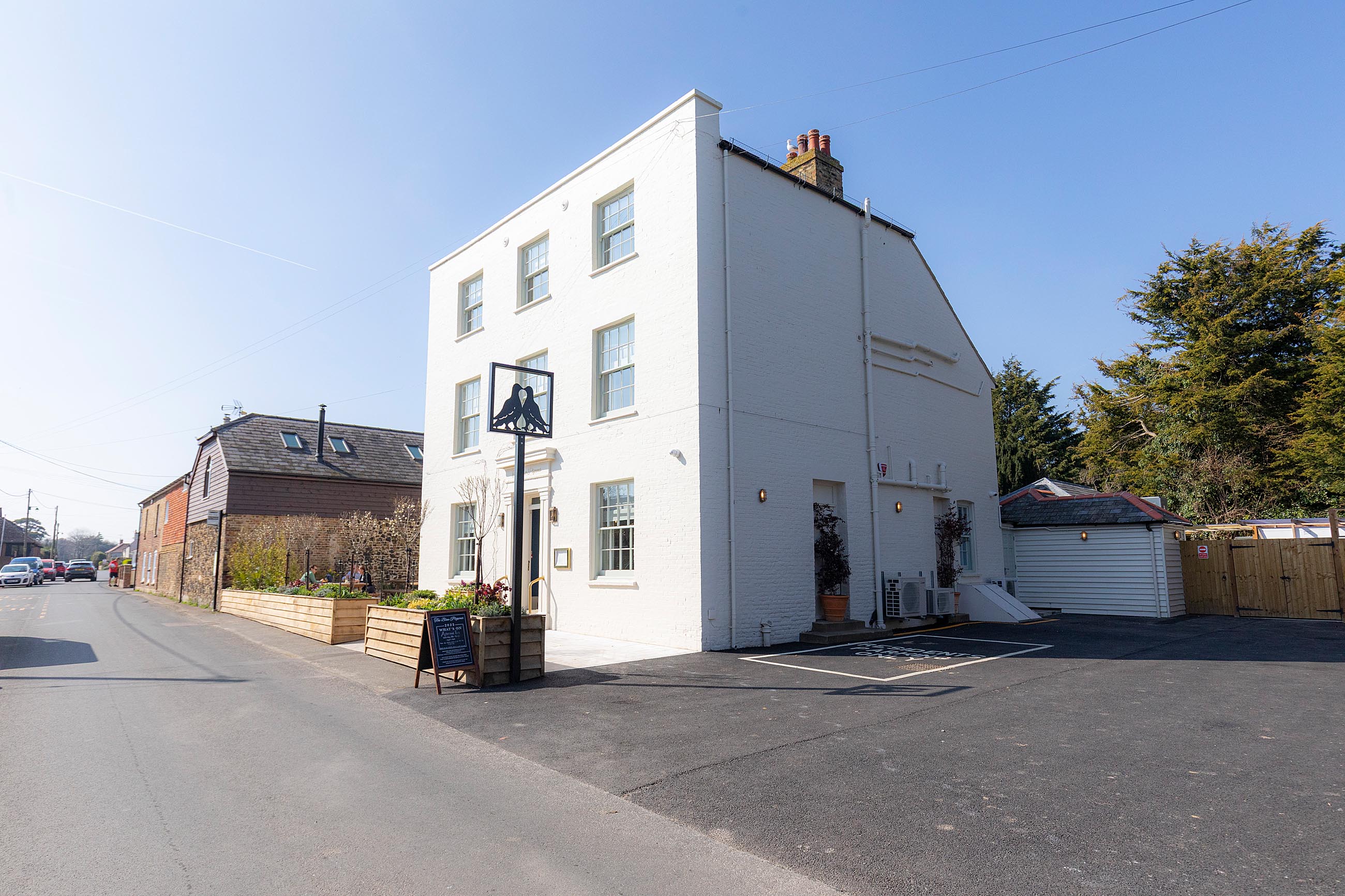 Exterior of hotel painted white with parking to the side