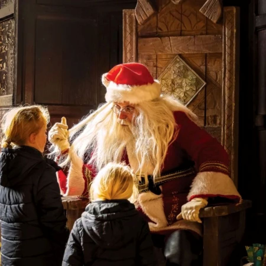 Chap dressed as Father Christmas talking to 2 little girls