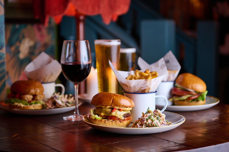 Plates of burgers and chips accompanied by a selection of drinks