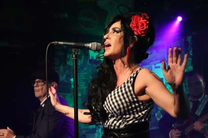 Caroline Lowe as Amy Winehouse on stage with a microphone