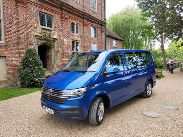 A blue VW van outside a historic brick building