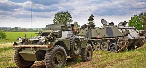 Image of a wartime tank and vintage military vehicle on a field