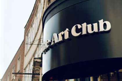 A rounded shop sign, The Art Club in white text on black
