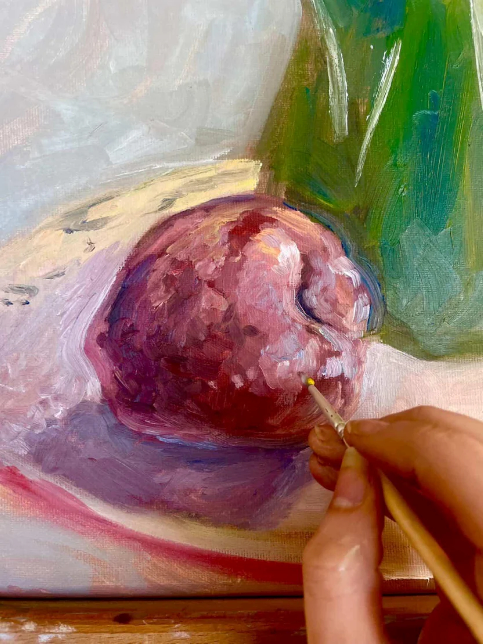 A hand with a paint brush painting an apple