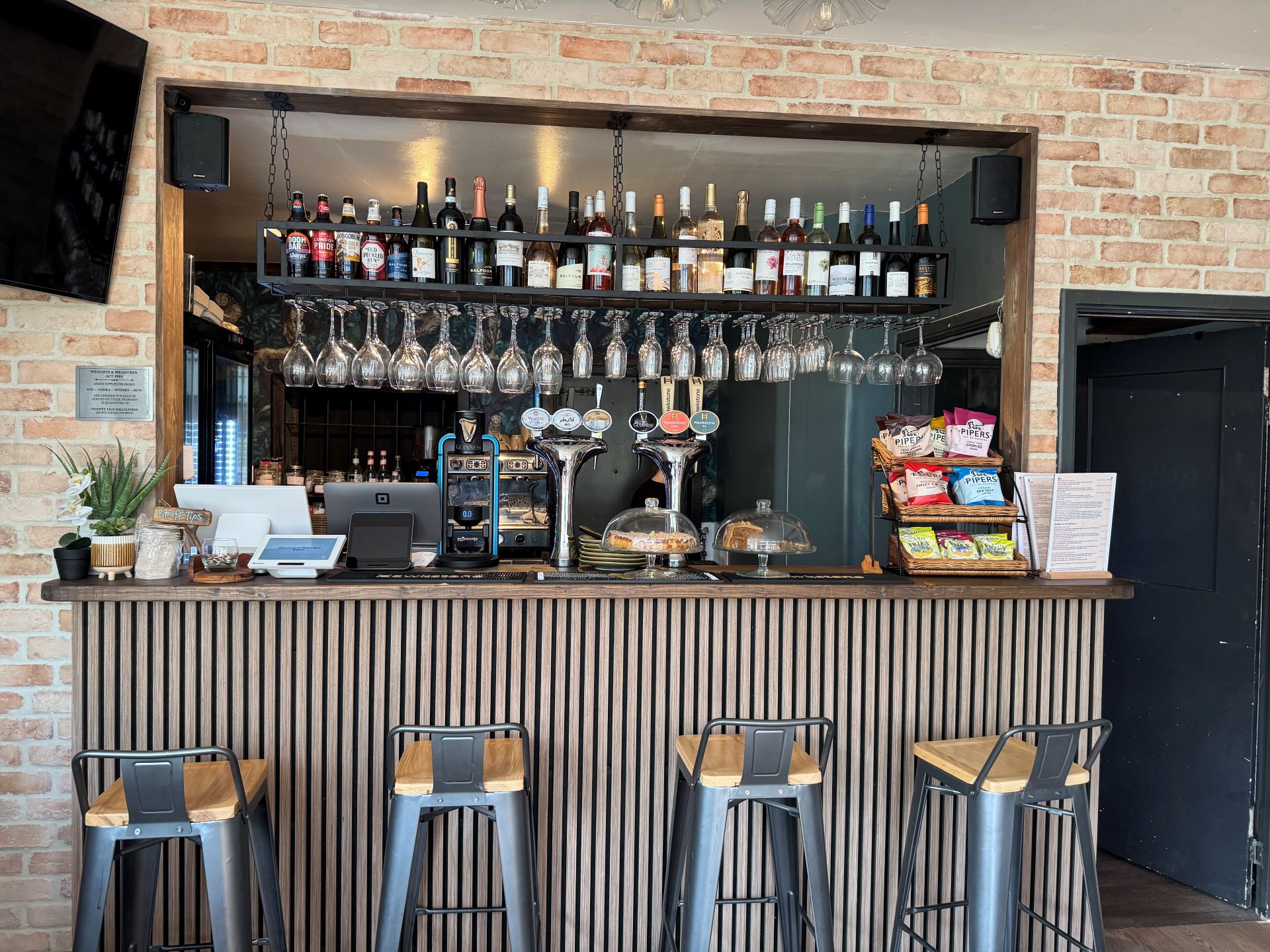 Wooden bar with stools, bottles and glasses above