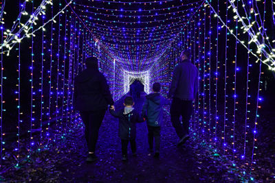 A family walking through Christmas lights trail