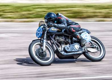 Image of a classic Norton bike being ridden on a race track