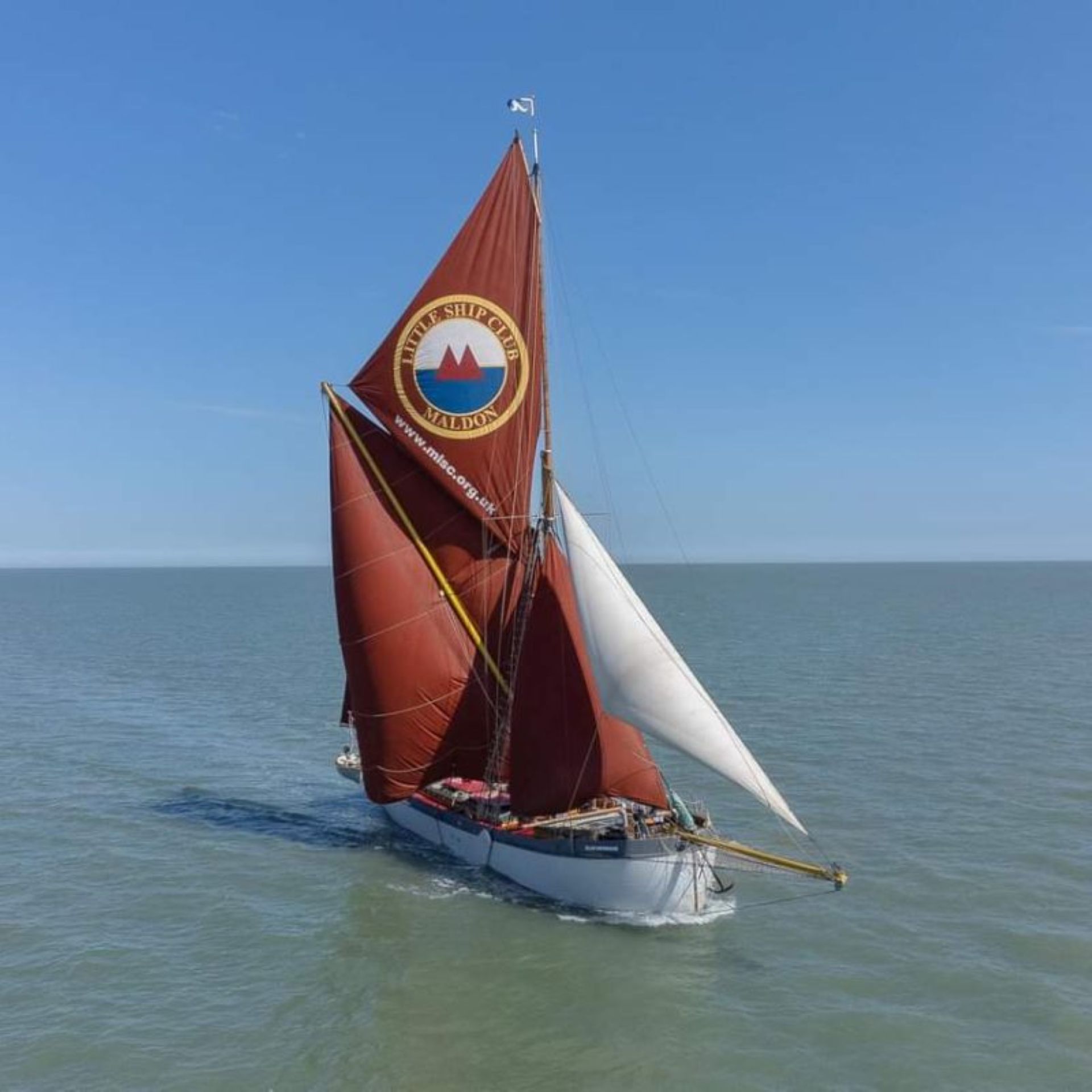 A Thames sailing barge with a red sail at sea