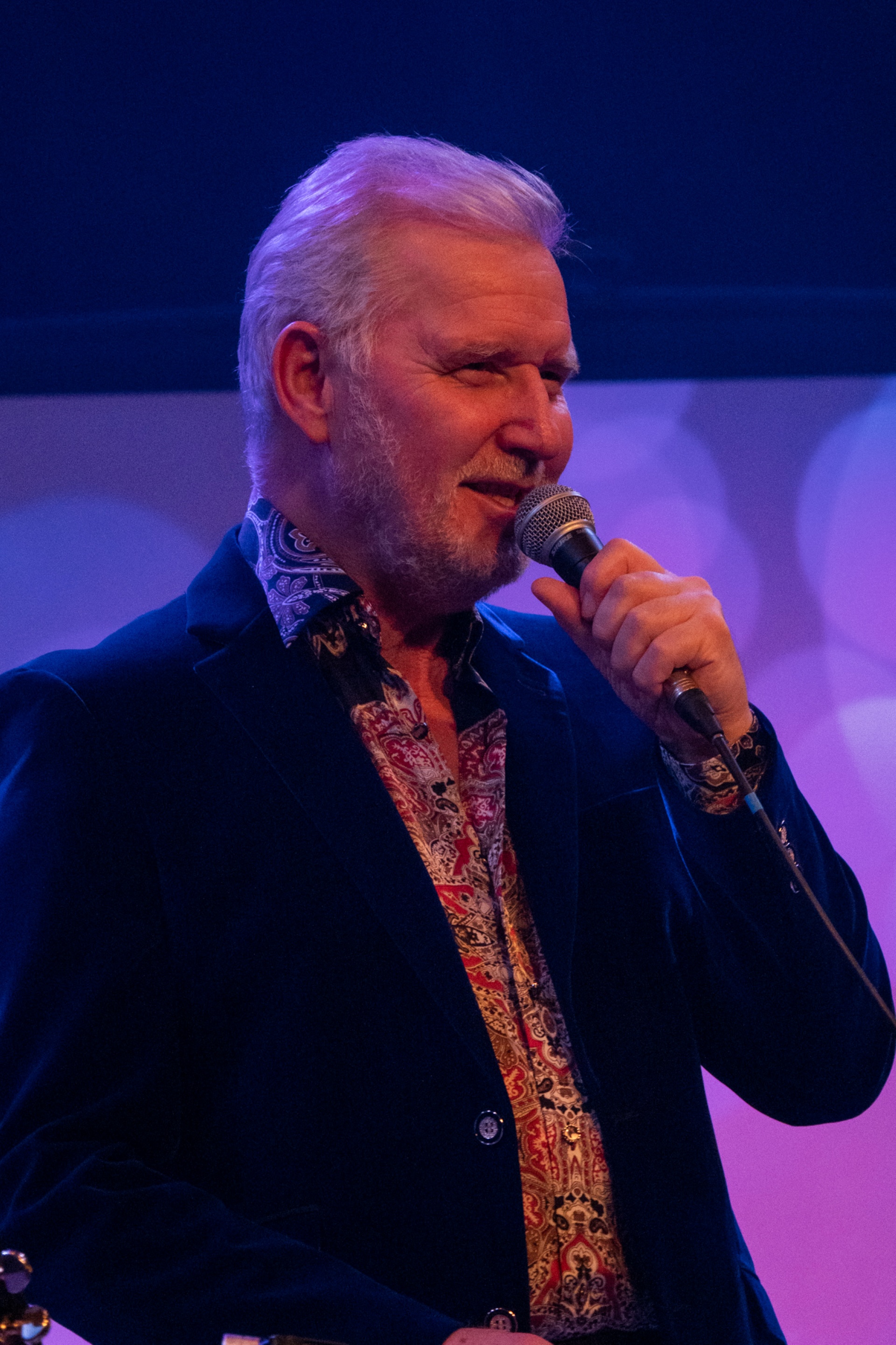 Bob Drury with a microphone on stage as Neil Diamond
