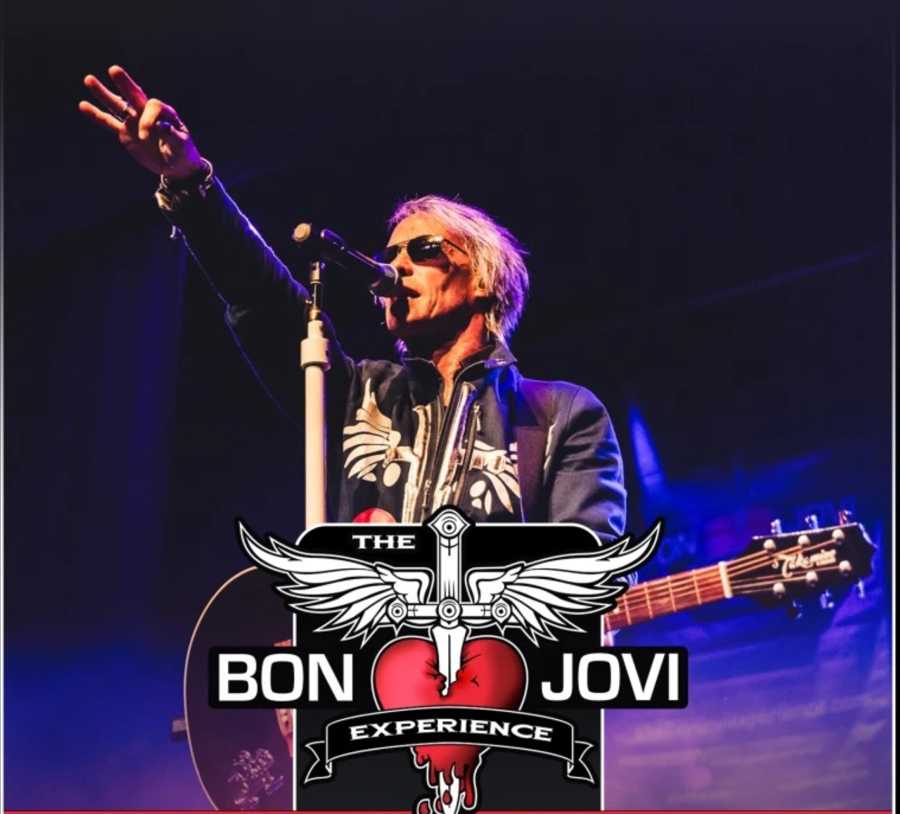 A male singer standing at a microphone with his hand in the air. The Bon Jovi Experience