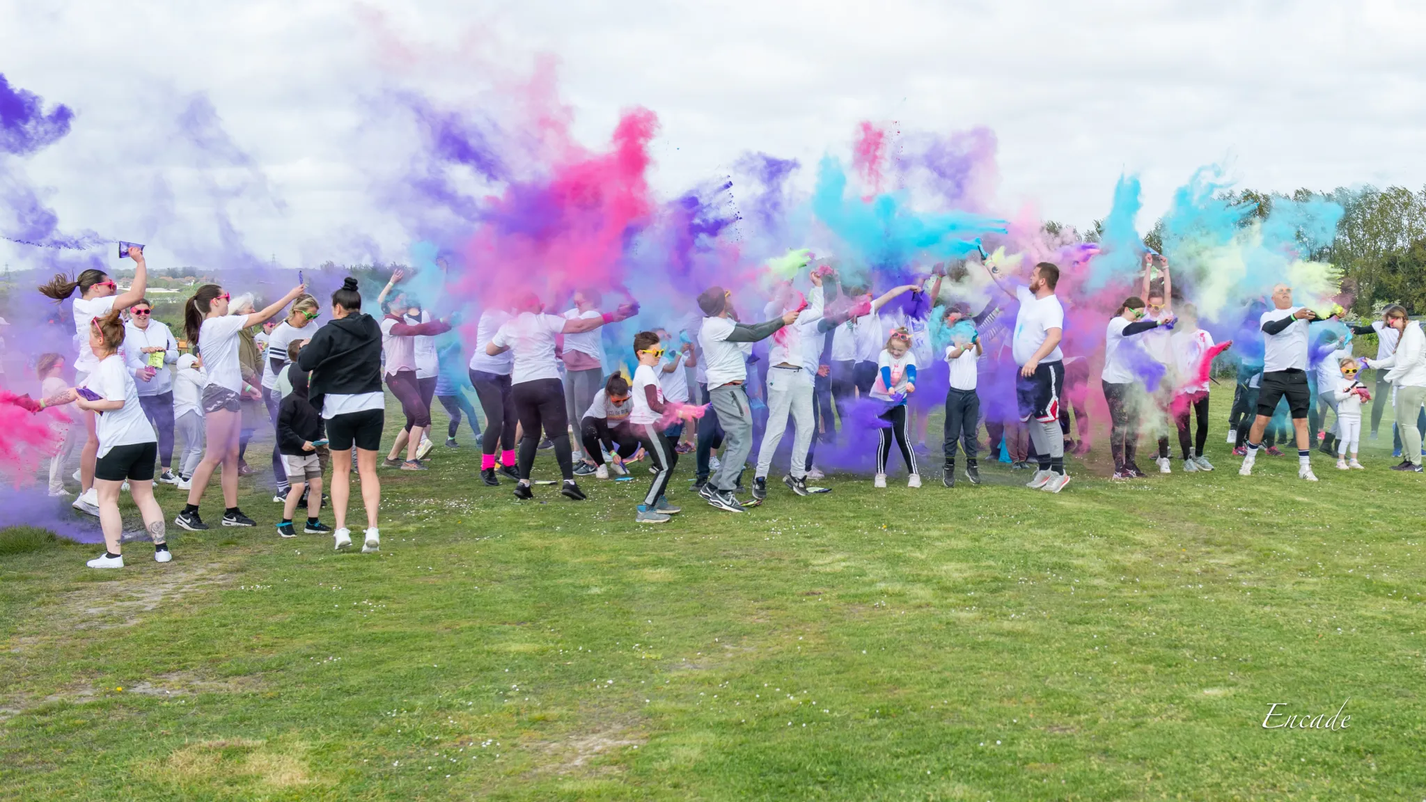 A crowd of people throwing colourful powder paint