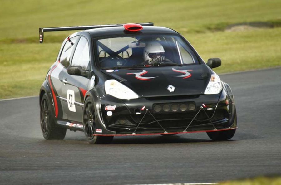 Photo of a black car driven by a racing driver going round a race track.