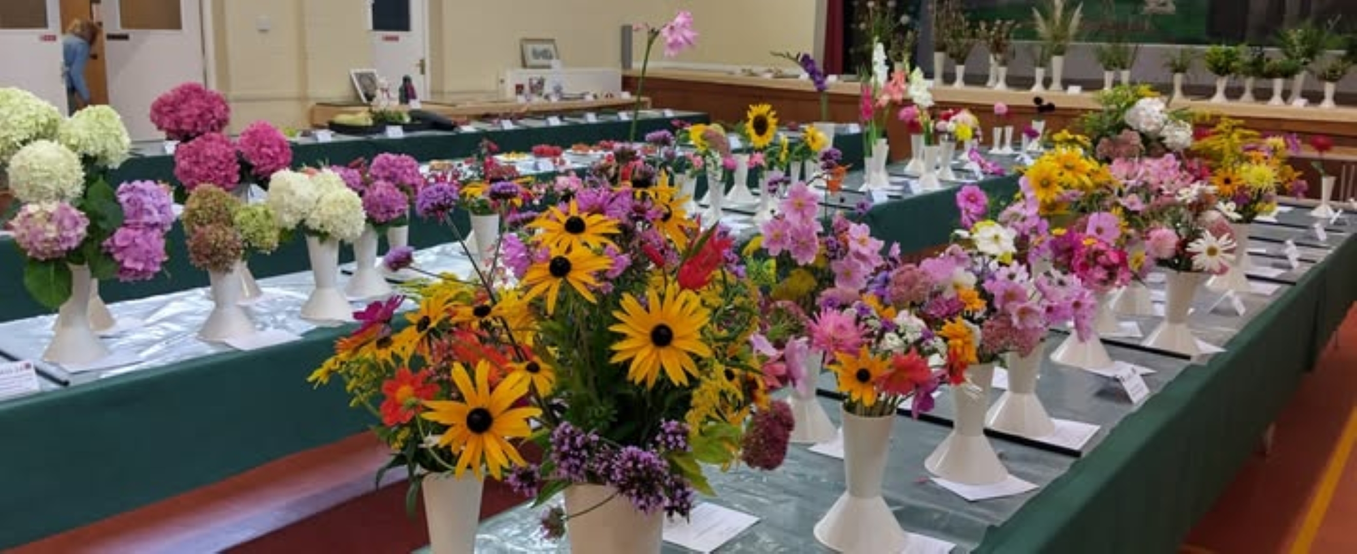 Tables displaying colourful flow displays in white vases