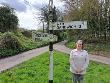 A woman standing beside a Ham Sandwich roadsign