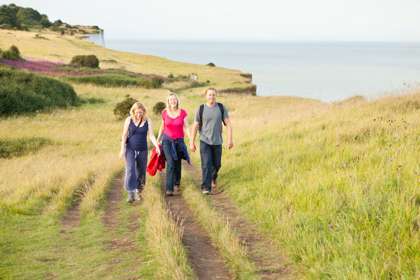 Three people walking along the clifftop towards the camera
