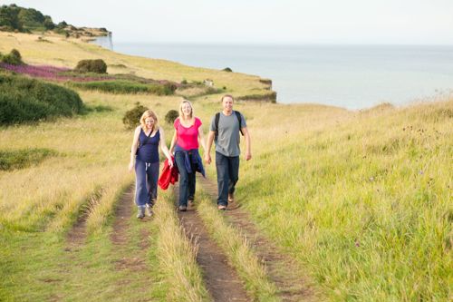 Three people walking towards the camera on the White Cliffs of Dover.