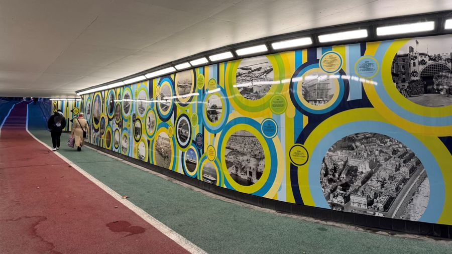 A couple walking through a brightly lit colourful underpass