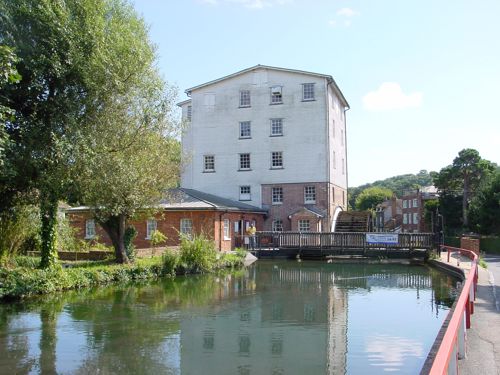 A mill with water wheel and a river in the foreground