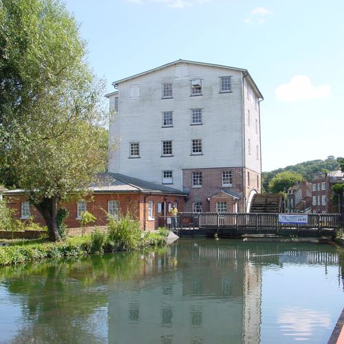 A mill with water wheel and a river in the foreground
