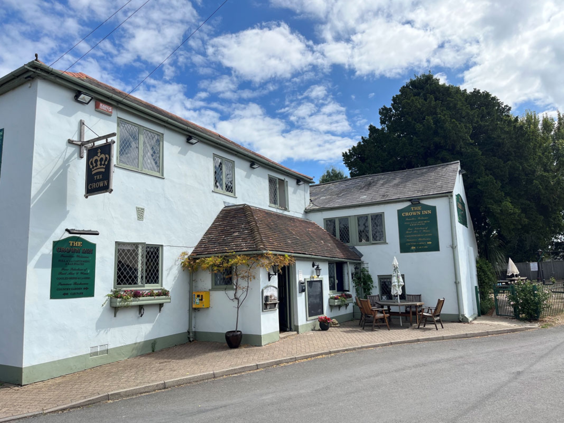 A white washed pub with a hanging sign The Crown