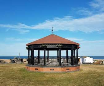 Photo of Deal Memorial Bandstand with blue sky and sea behind