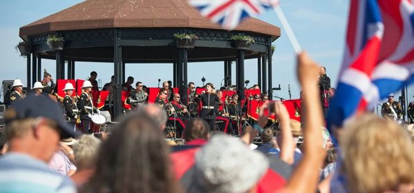 A band on Deal Memorial Bandstand and the crowd waving Union Jacks.