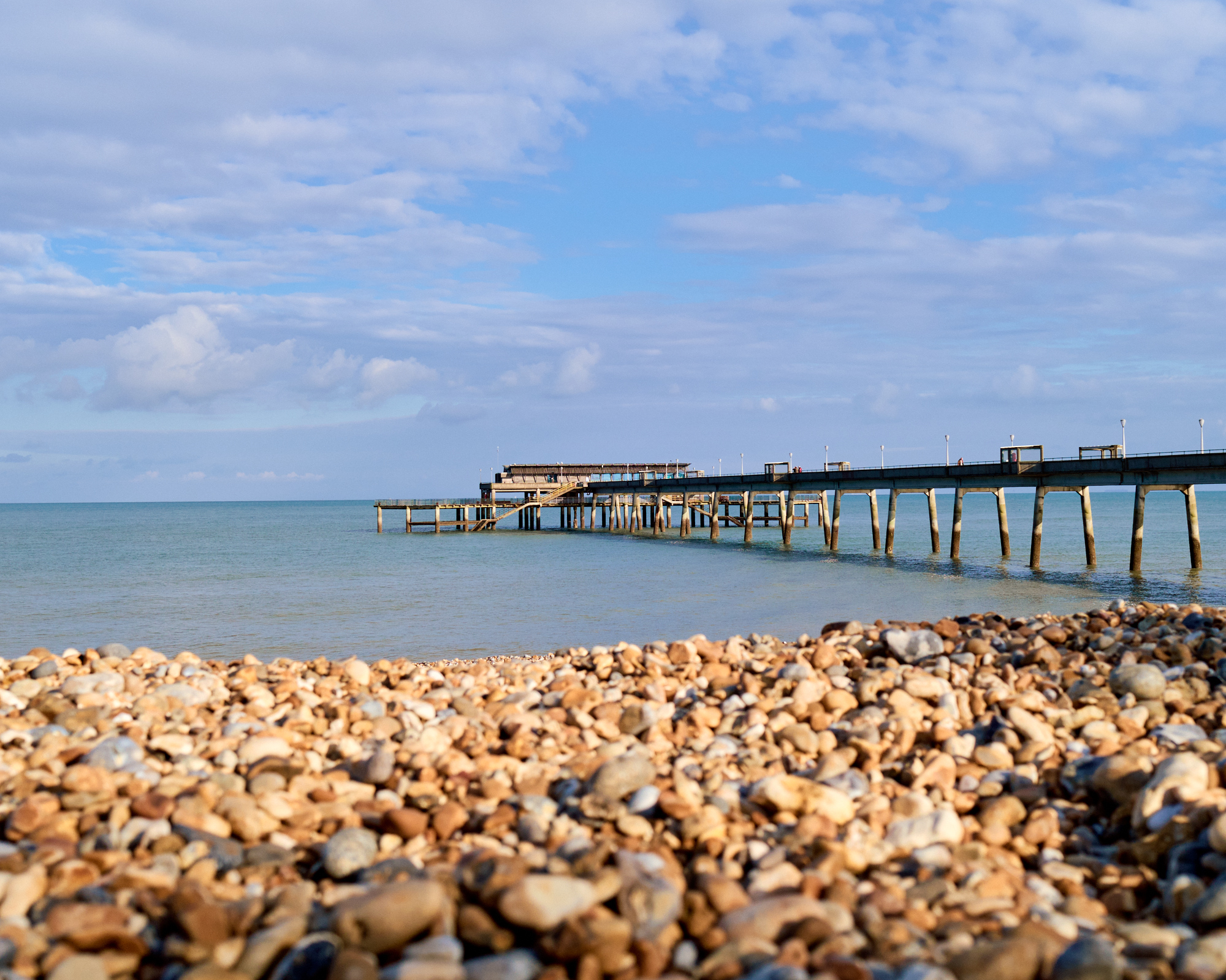 A stony beach with a concrete pier