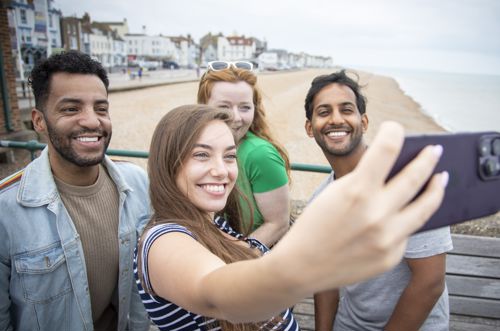 Four people taking a selfie with Deal seafront in the background.