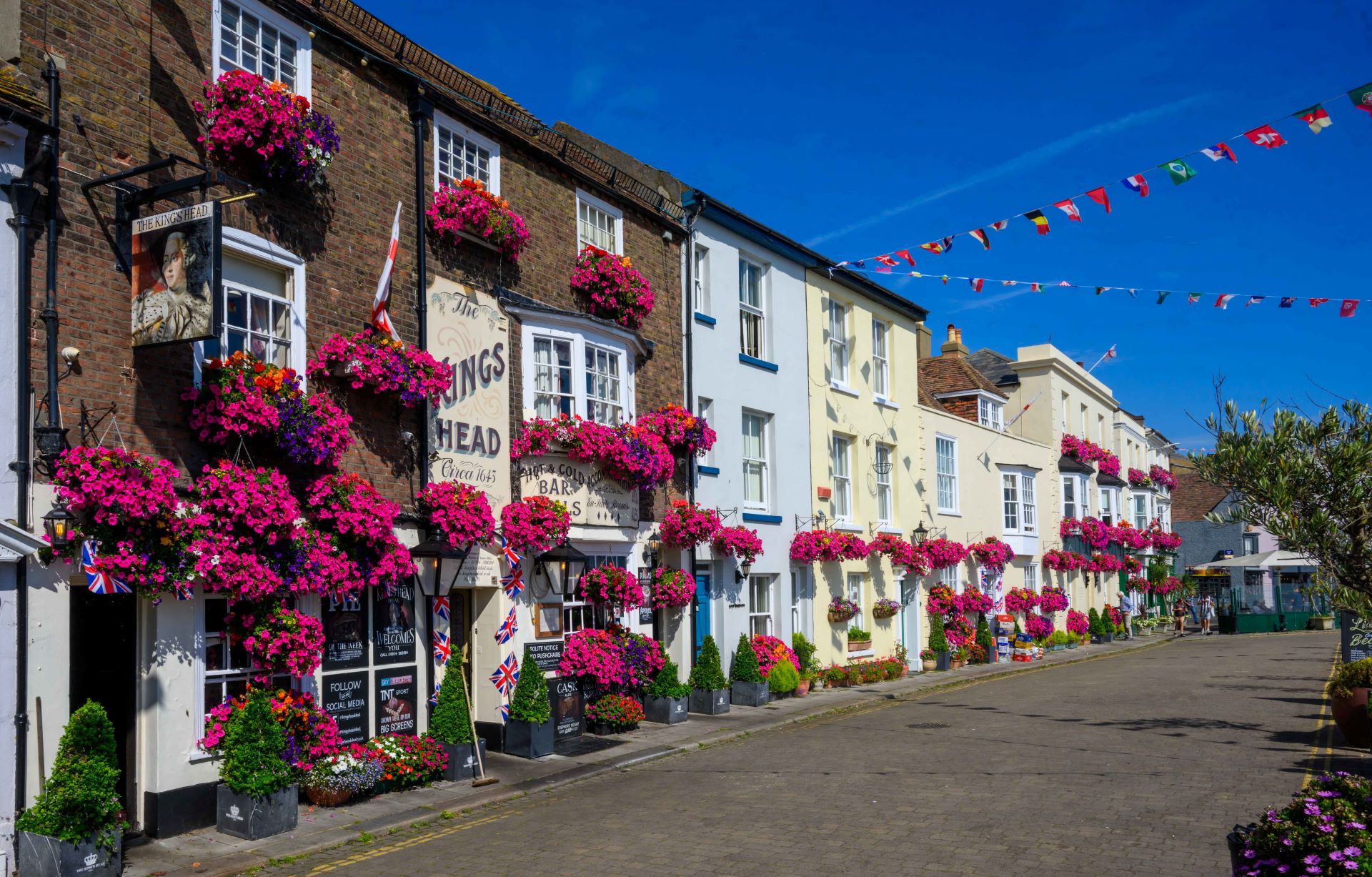 A row of Georgian fronted pubs with pink hanging baskets.